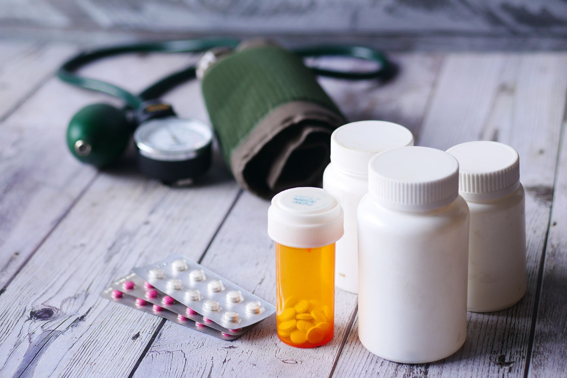 Prescription bottles and a blood-pressure cuff on a desk