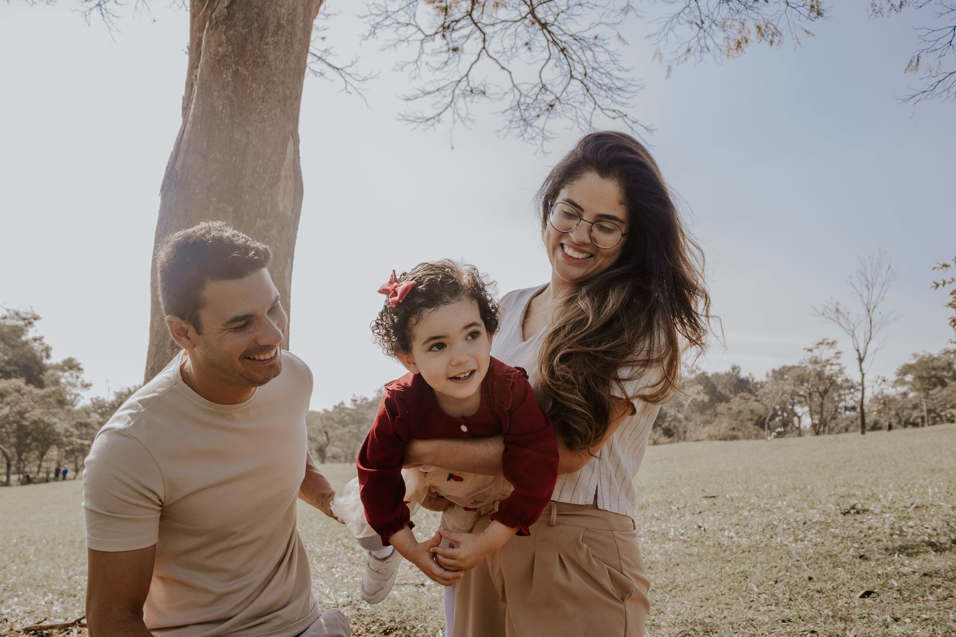 Two parents outdoors with their small daughter, laughing together